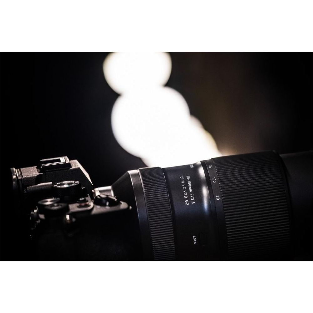 Aparat z długim obiektywem skierowany w stronę rozmytych świateł w tle.