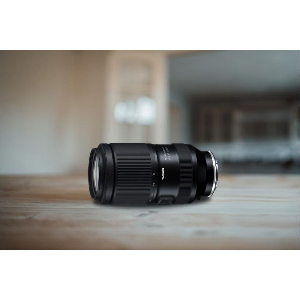 Czarny obiektyw Tamron leży na drewnianym stole.
