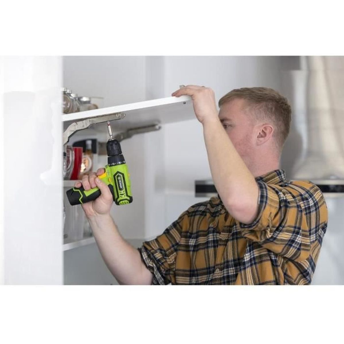 Mężczyzna przykręca półkę w szafce wiertarką.