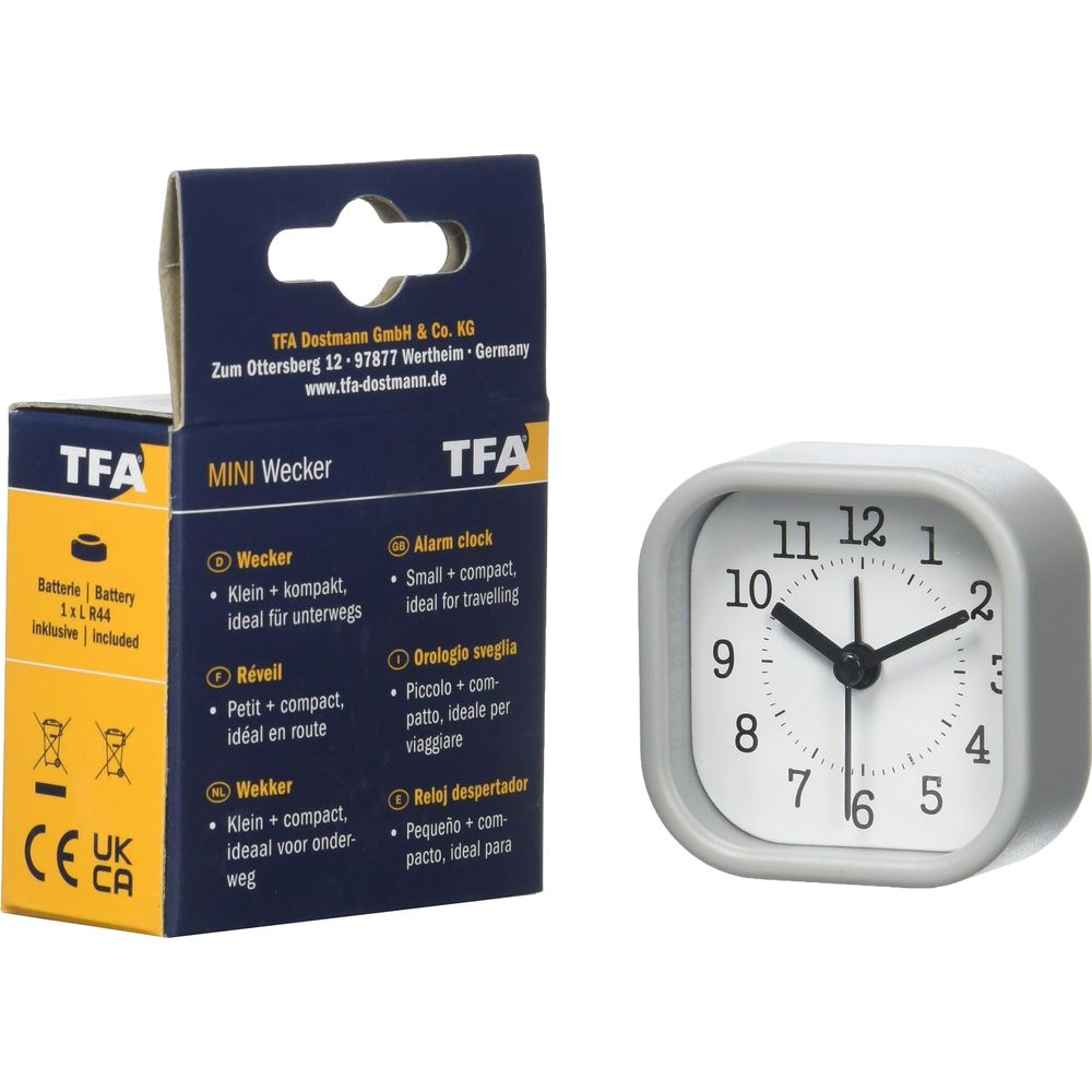 Grauer Wecker mit weißem Zifferblatt und schwarzen Zeigern, daneben Verpackung.