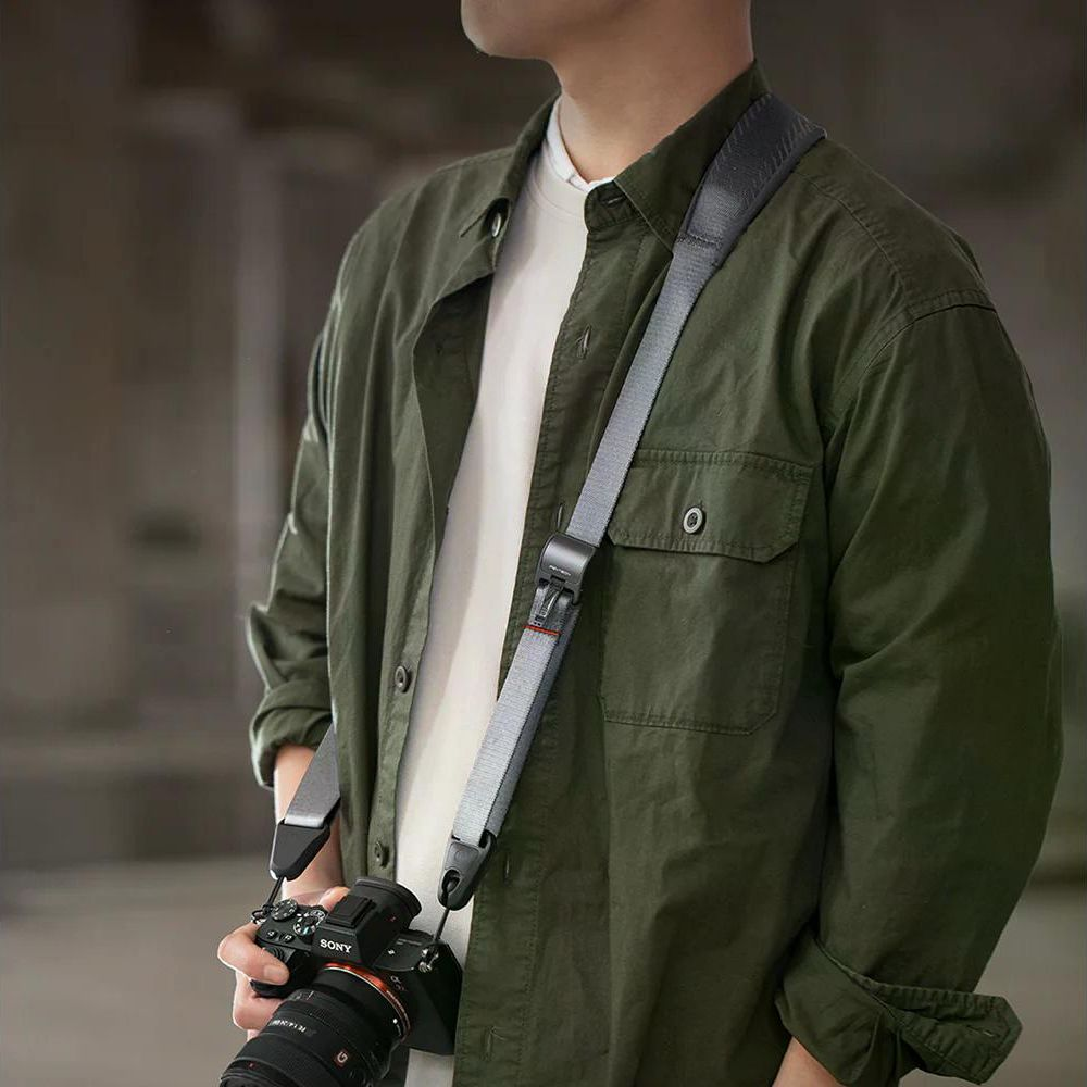 Mężczyzna w zielonej koszuli z aparatem i paskiem.