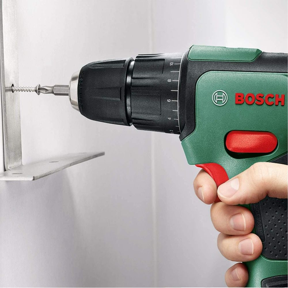 Una mano tiene un trapano Bosch verde, avvitando una vite in una staffa metallica.