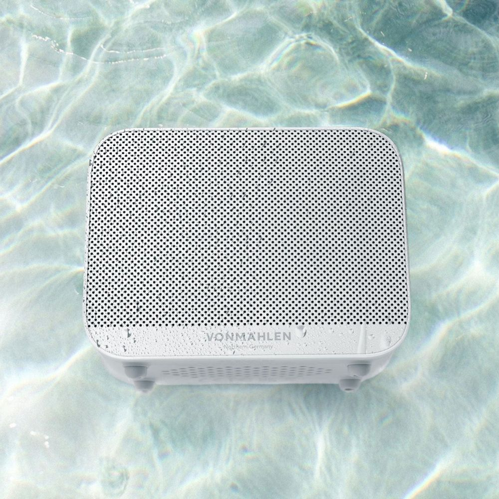 Ein weißer Lautsprecher schwimmt im klaren Wasser mit Lichtreflexionen.