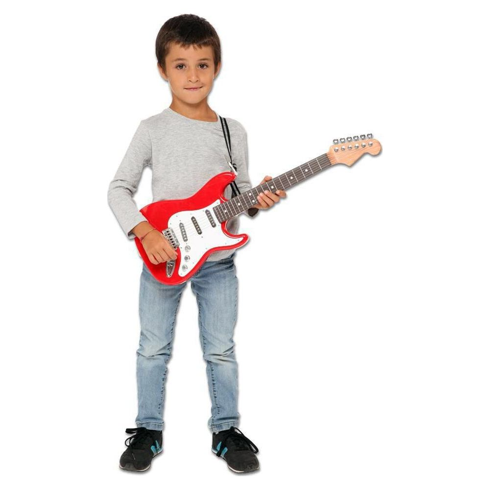 Chłopiec w dżinsach i szarej koszulce trzyma czerwoną gitarę zabawkę.