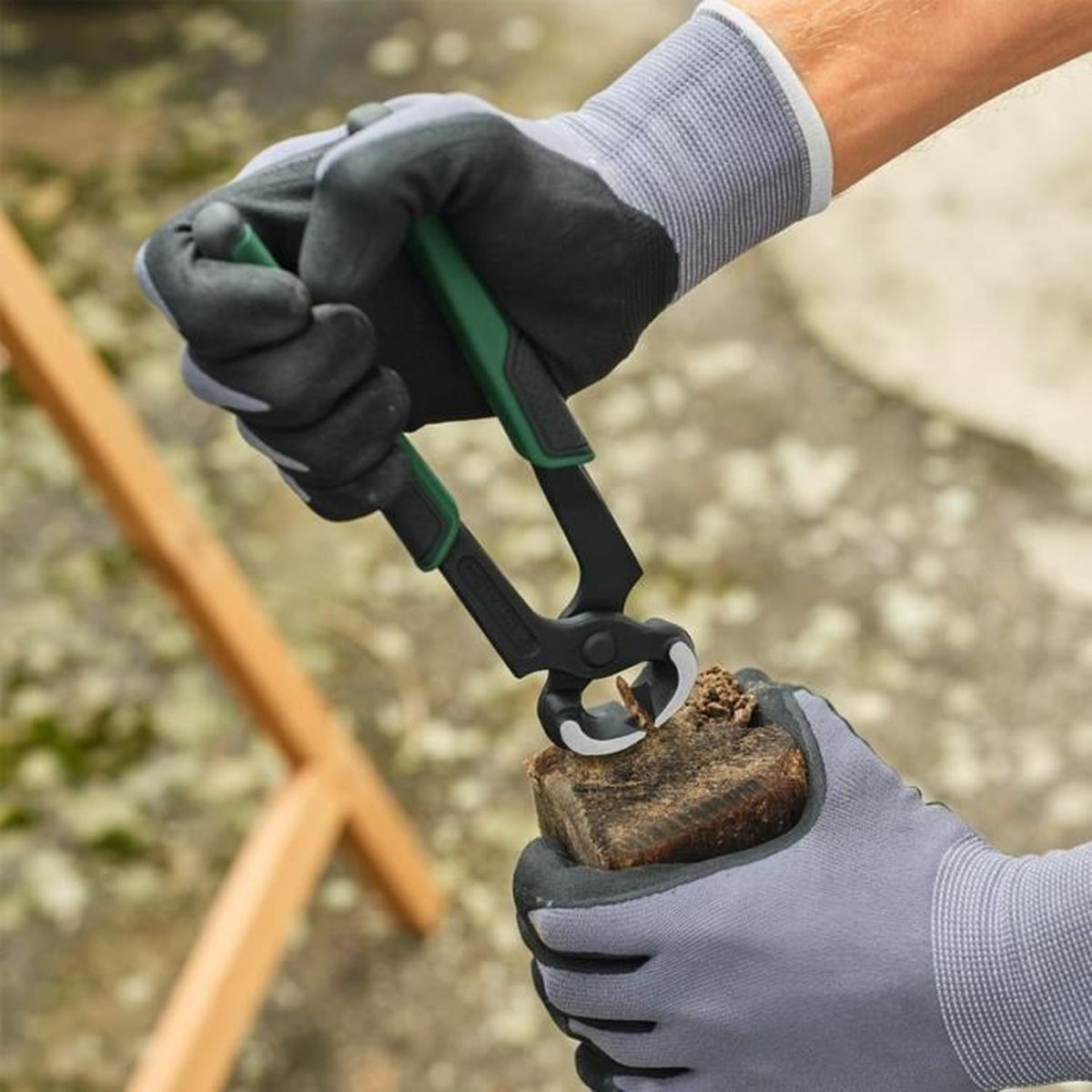 Hände in grauen Handschuhen benutzen Zange zum Schneiden eines Holzstücks.