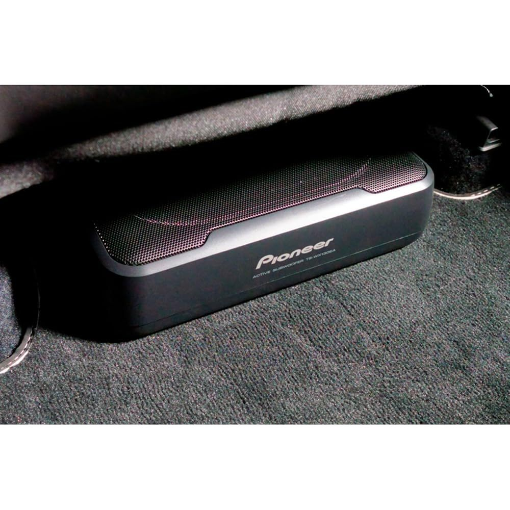 Un subwoofer Pioneer sotto un sedile dell'auto su tappeto grigio.