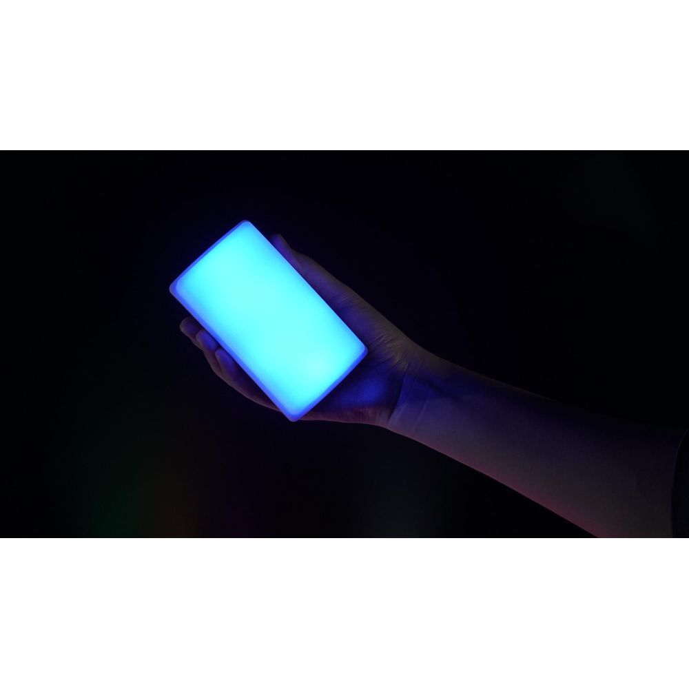 Une main tient un cylindre bleu lumineux sur fond sombre.