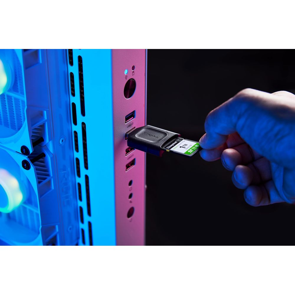 Dłoń wkłada kartę SD 1TB do adaptera USB podłączonego do komputera.