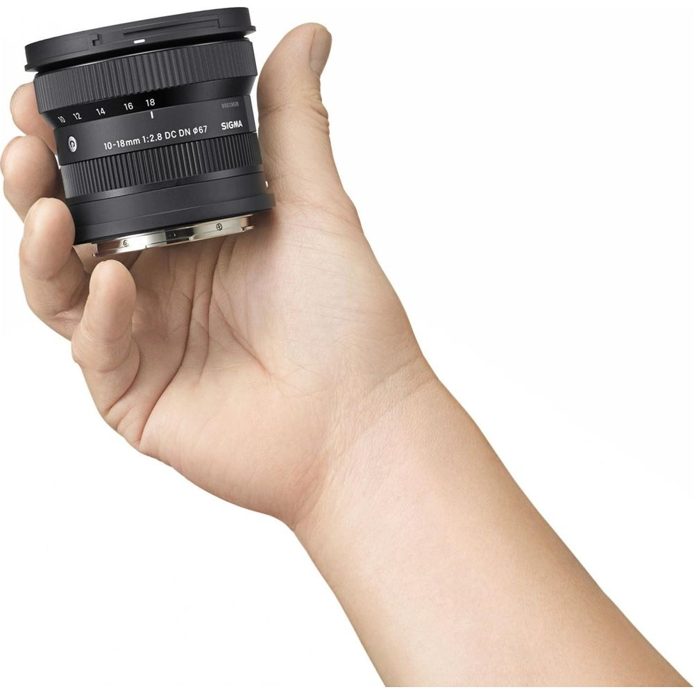 Una mano tiene un obiettivo Sigma 10-18mm con segni di lunghezza focale visibili.