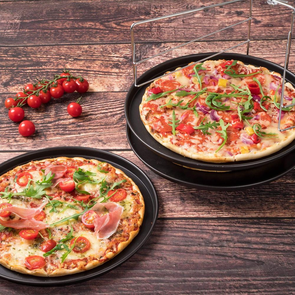 Zwei Pizzen auf Holzhintergrund mit Kirschtomaten. Eine Pizza ist mit Schinken belegt.