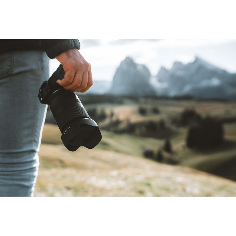 Osoba trzyma aparat fotograficzny w górzystym krajobrazie.