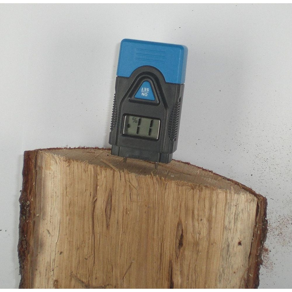 Ein Holzfeuchtemessgerät steckt in einem Holzstück, das Display zeigt 11%.