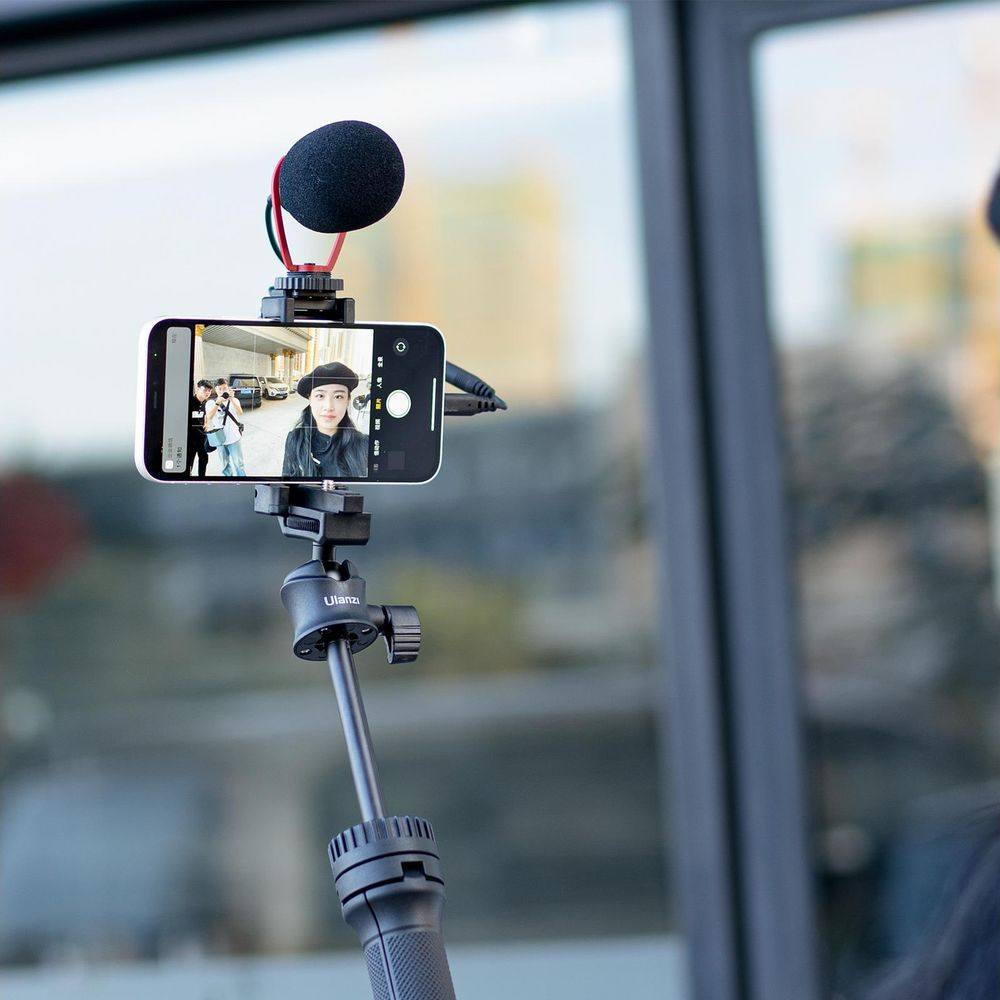 Smartfon na statywie z mikrofonem robi sobie selfie.