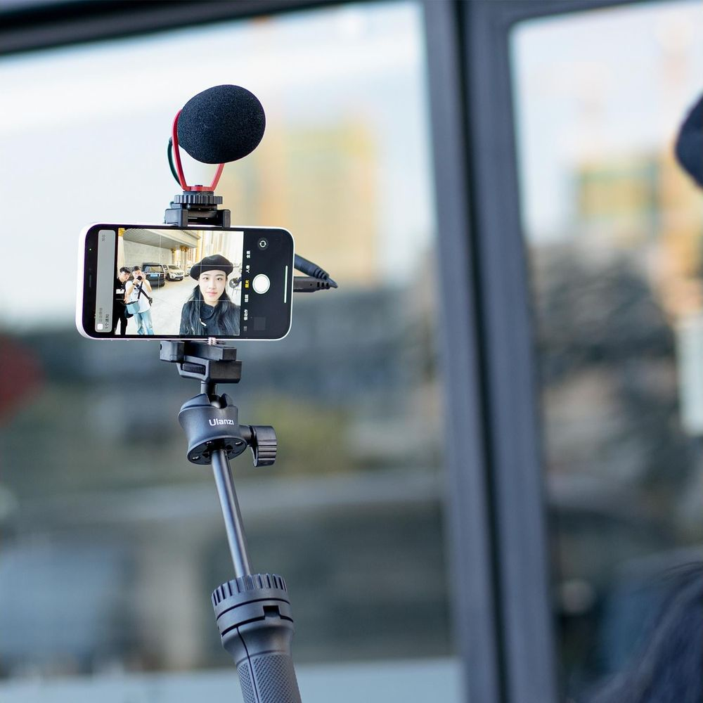 Smartfon na statywie filmuje kobietę w czarnym beretem.