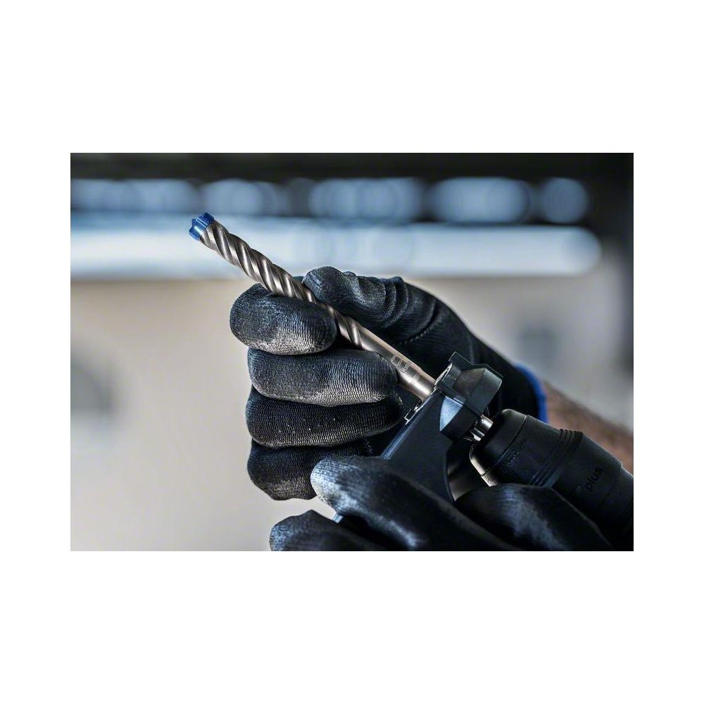 Ręce w czarnych rękawicach trzymają wiertło w młocie udarowym.