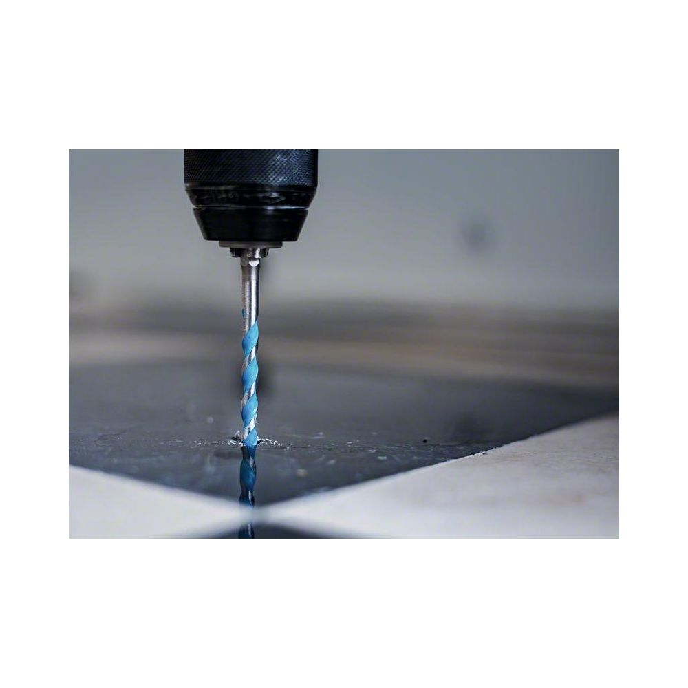 Niebieski wiertło spiralne wierci w ciemnej powierzchni.