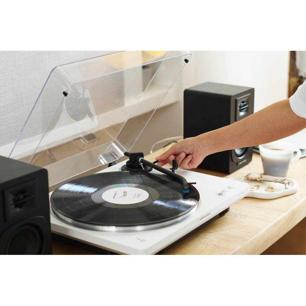 Ręka opuszcza igłę gramofonu na czarną płytę winylową.