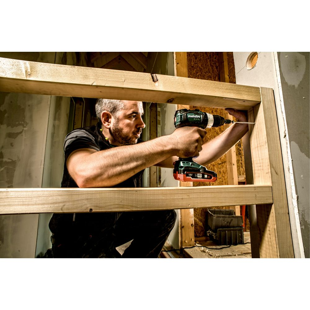 Mężczyzna używa wiertarko-wkrętarki do skręcania drewna.