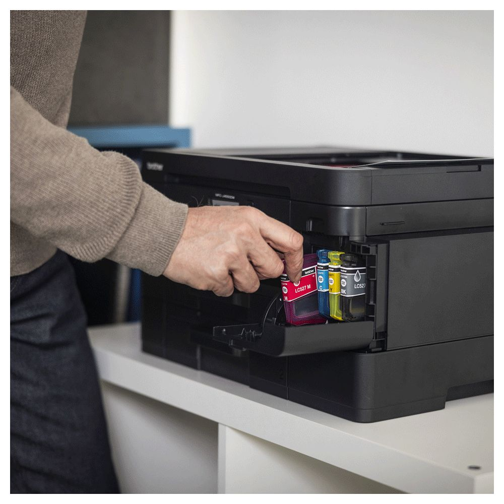 Mężczyzna wkłada czerwoną kasetę z tuszem do drukarki.