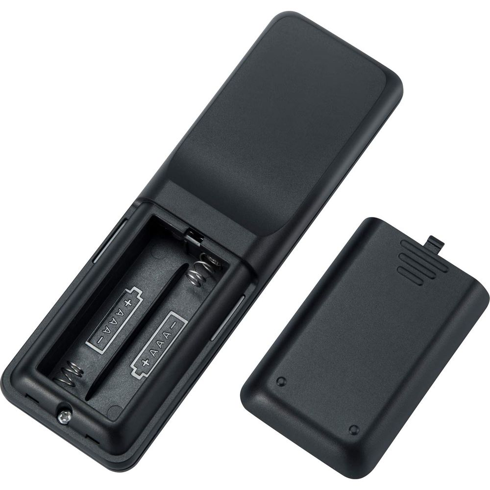 Ein schwarzer Fernbedienungsdeckel liegt neben einem offenen Batteriefach.