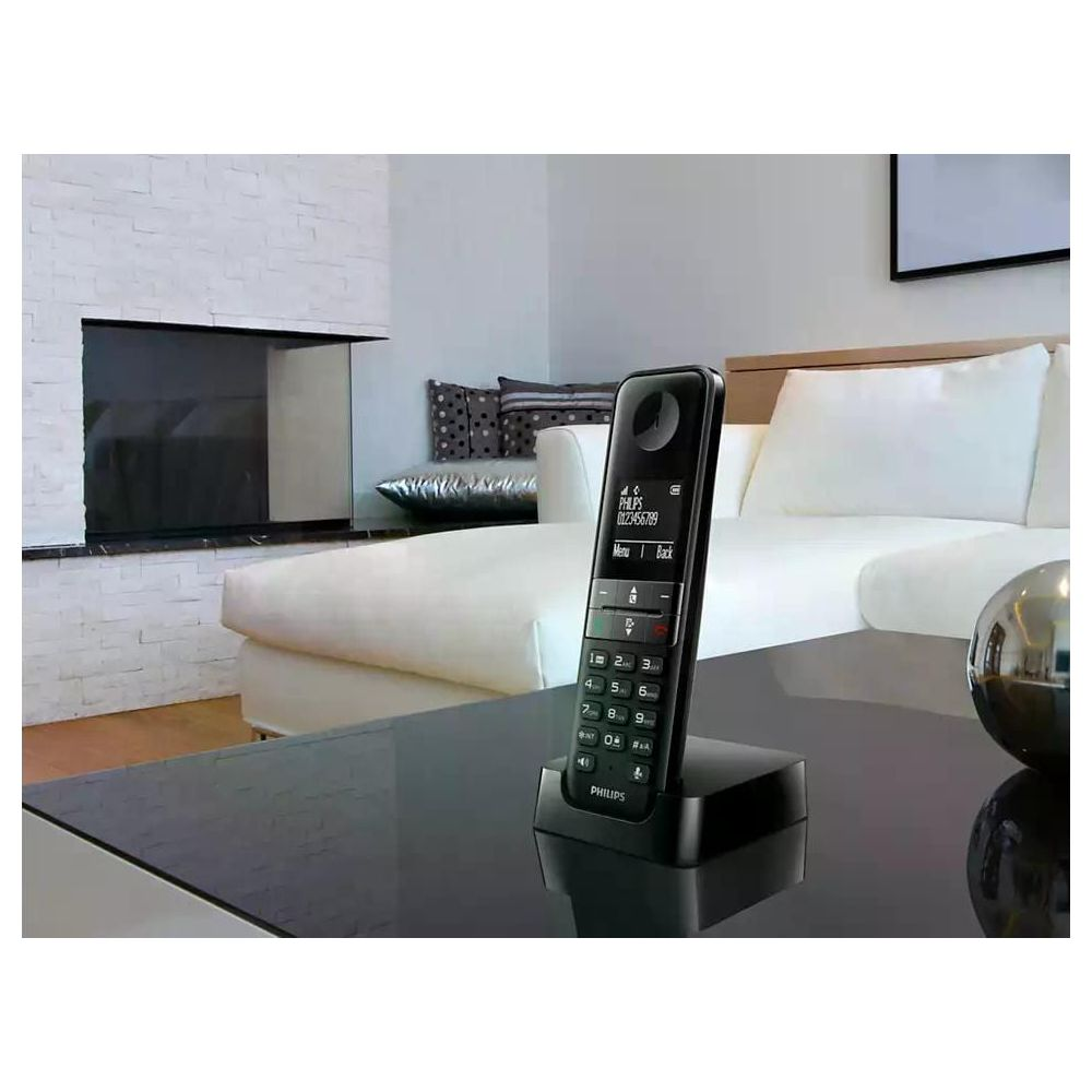 Un téléphone sans fil Philips noir repose sur une table noire.
