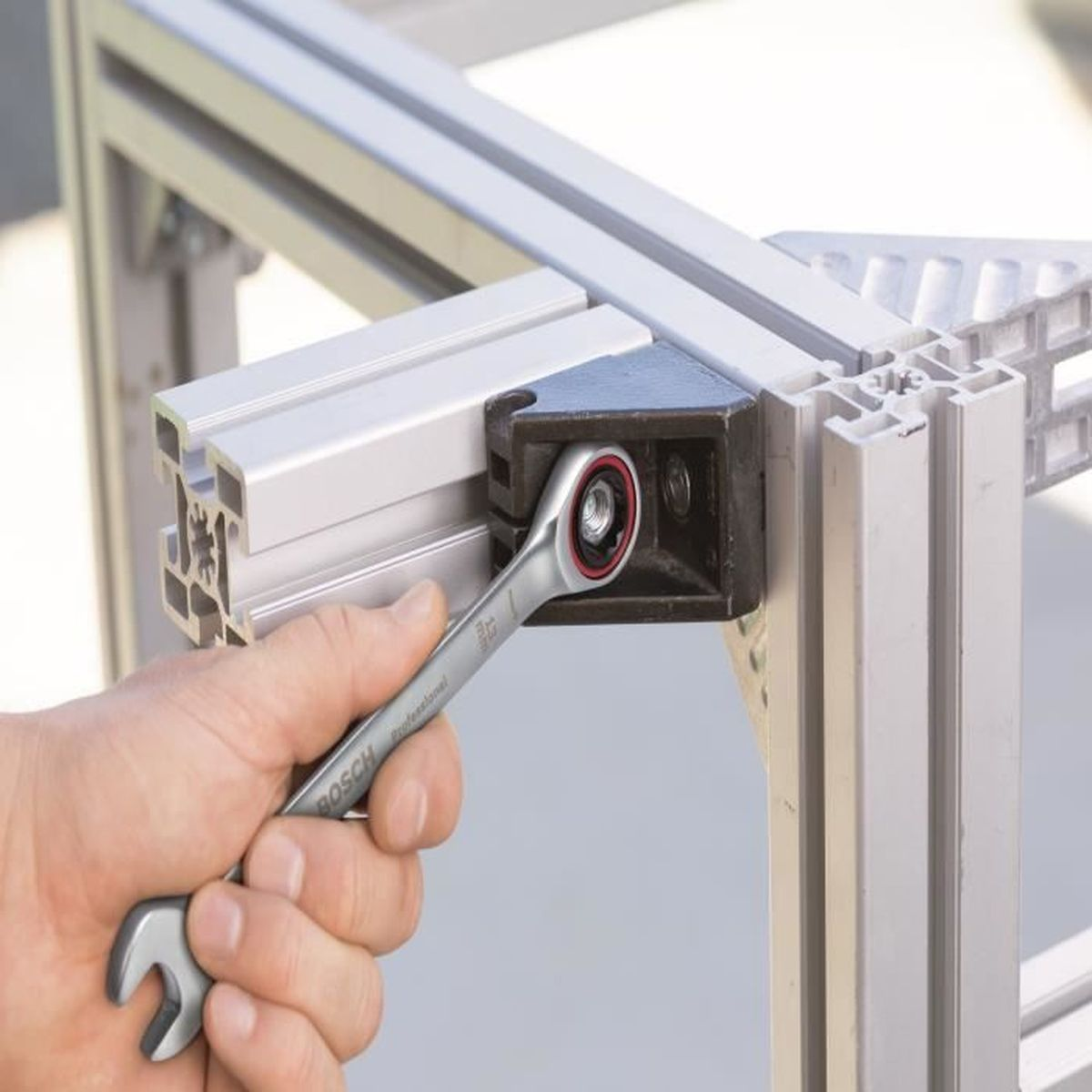 Eine Hand benutzt einen Ratschenschlüssel, um eine Aluminiumkonstruktion zu befestigen.