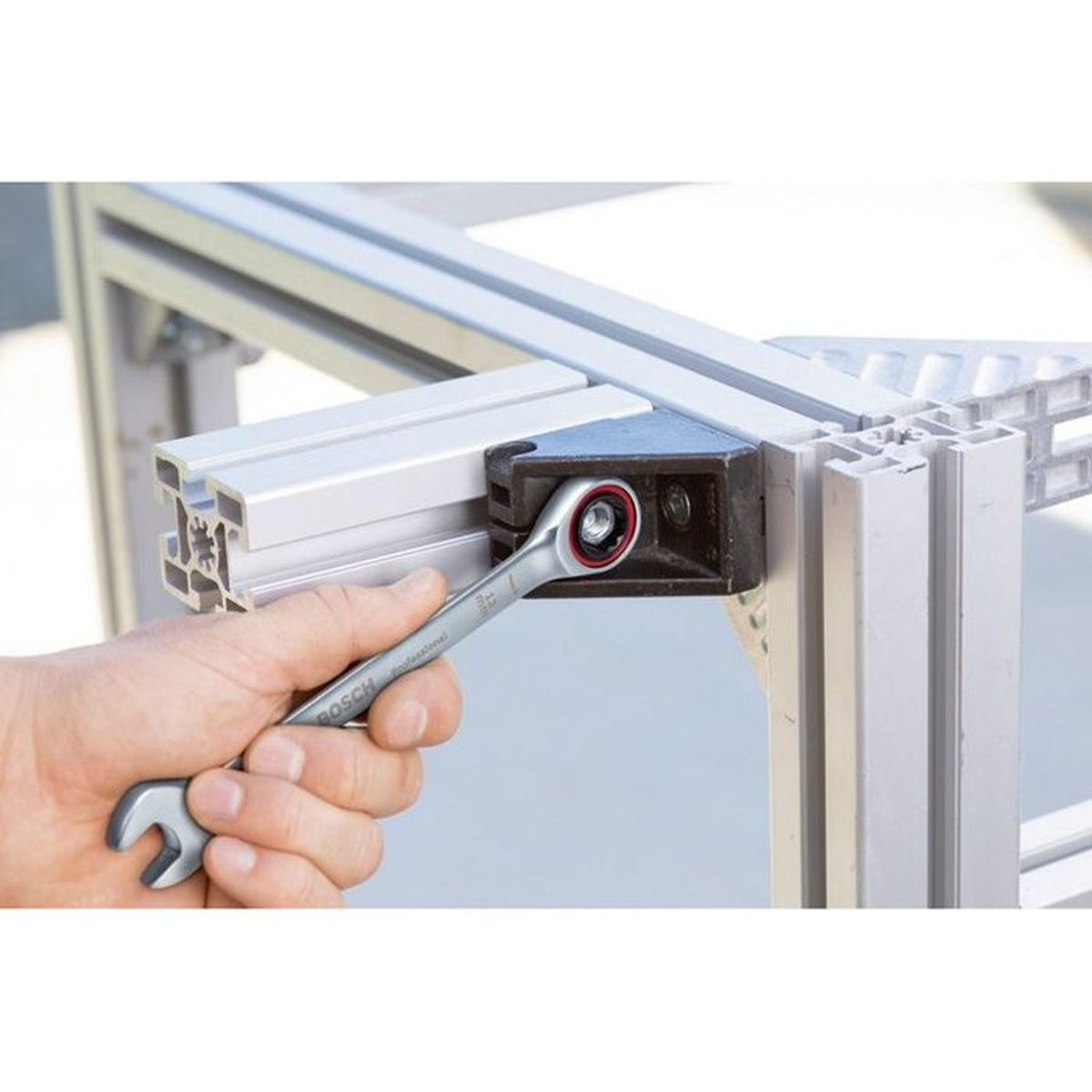Hand benutzt Ratschenschlüssel, um ein Aluminiumprofil zu befestigen.