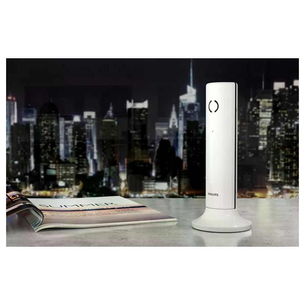 Un téléphone sans fil blanc sur une table, avec la ligne d'horizon d'une ville la nuit.