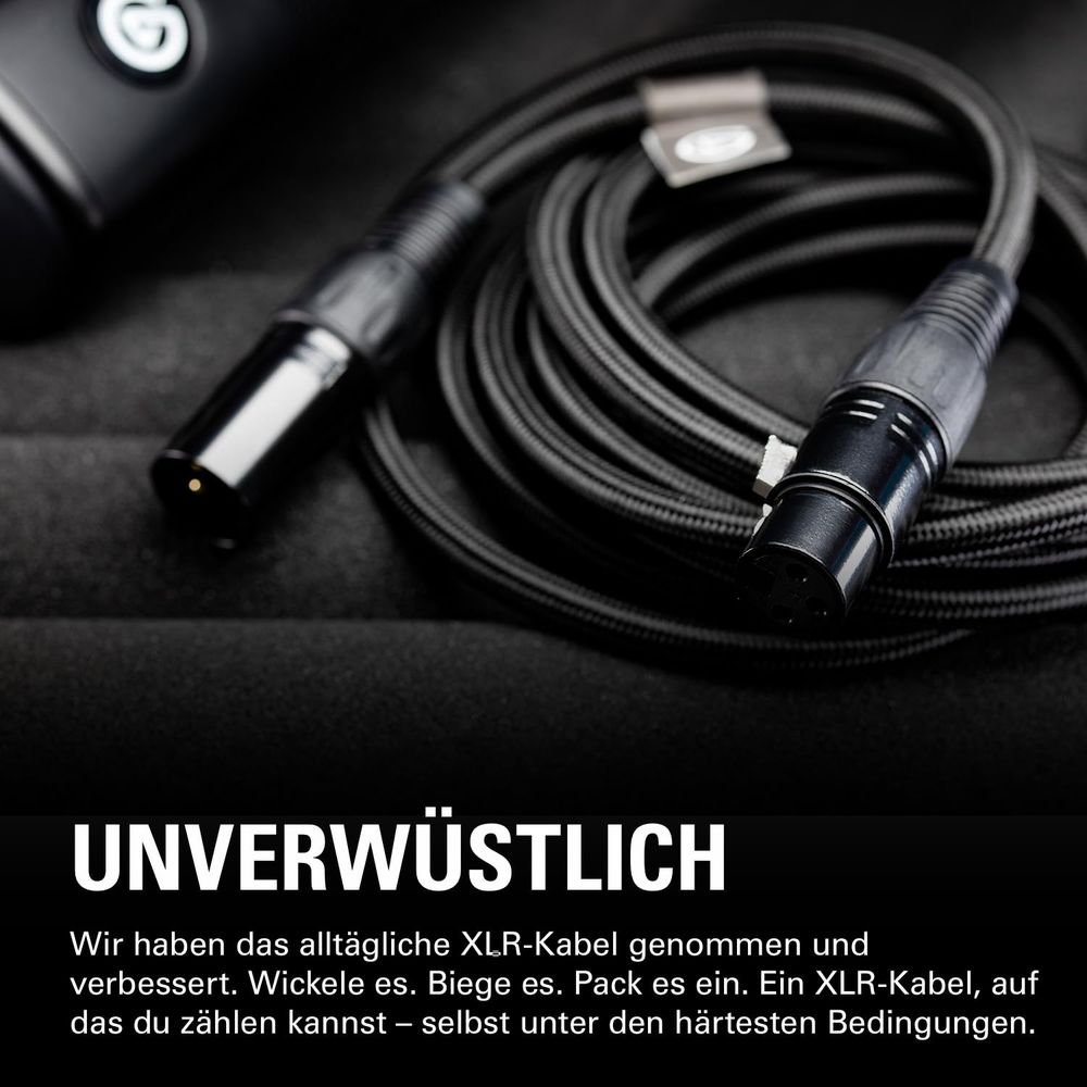 Schwarzes XLR-Kabel mit zwei Steckern, liegend auf schwarzem Stoff.