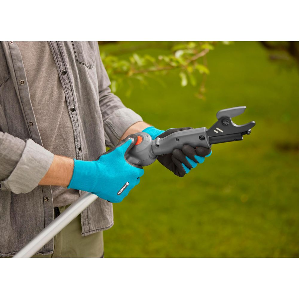 Person mit blauen Handschuhen hält Gartenschere mit Verlängerungsstiel.