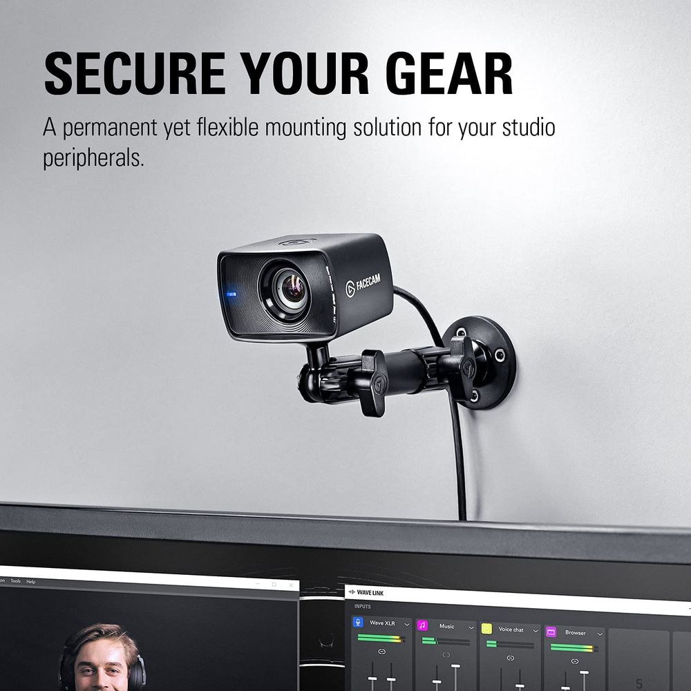 Eine schwarze FACECAM-Webcam ist an einer Wand montiert, über einem Computermonitor.