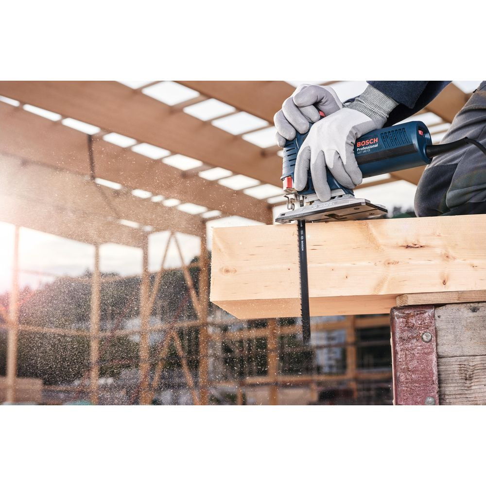 Rzemieślnik tnie drewno niebieską wyrzynarką Bosch.