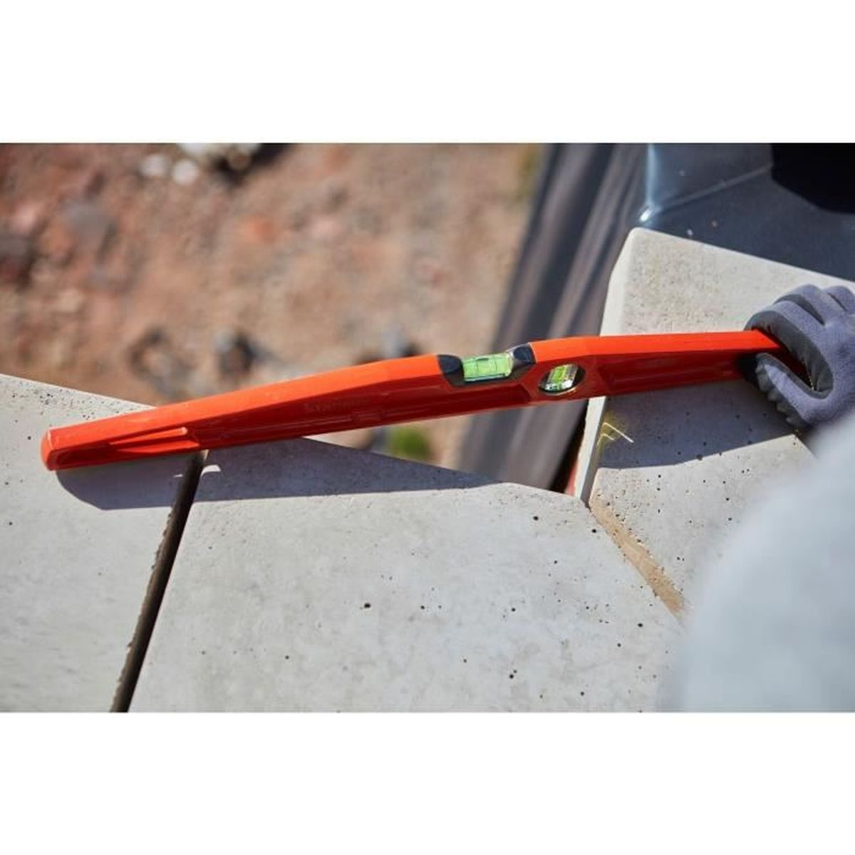 Orange Wasserwaage auf Beton mit behandschuhten Hand. Blase zentriert.