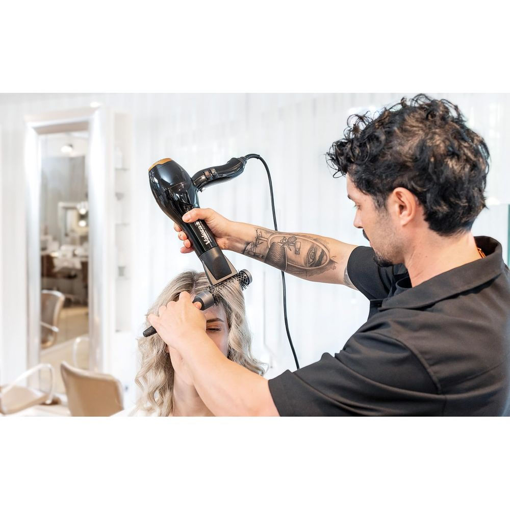 Fryzjer suszy i szczotkuje blond włosy klientki w salonie.