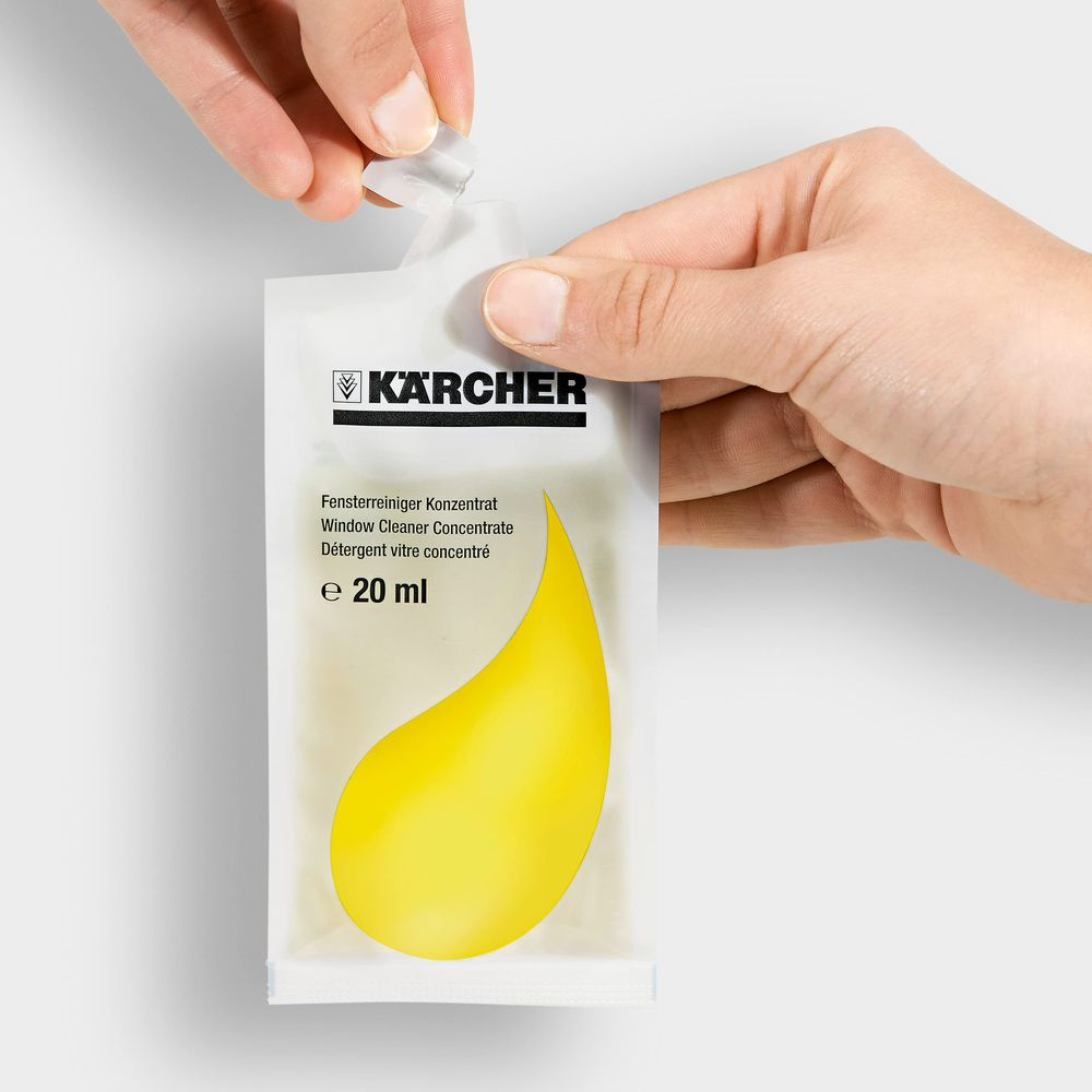 Una mano abre un paquete de concentrado limpiacristales Kärcher de 20 ml.