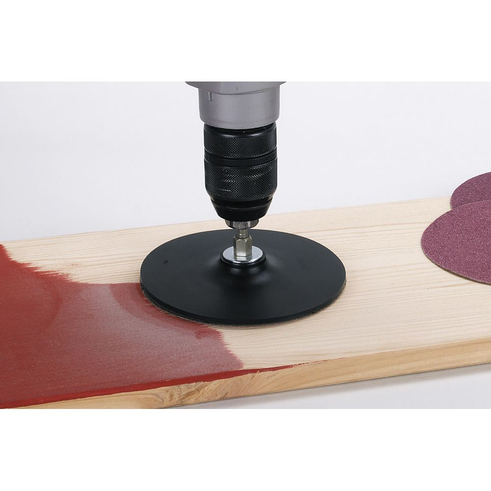 Bohrmaschine mit Schleifscheibe auf Holz, teilweise rot gefärbt.