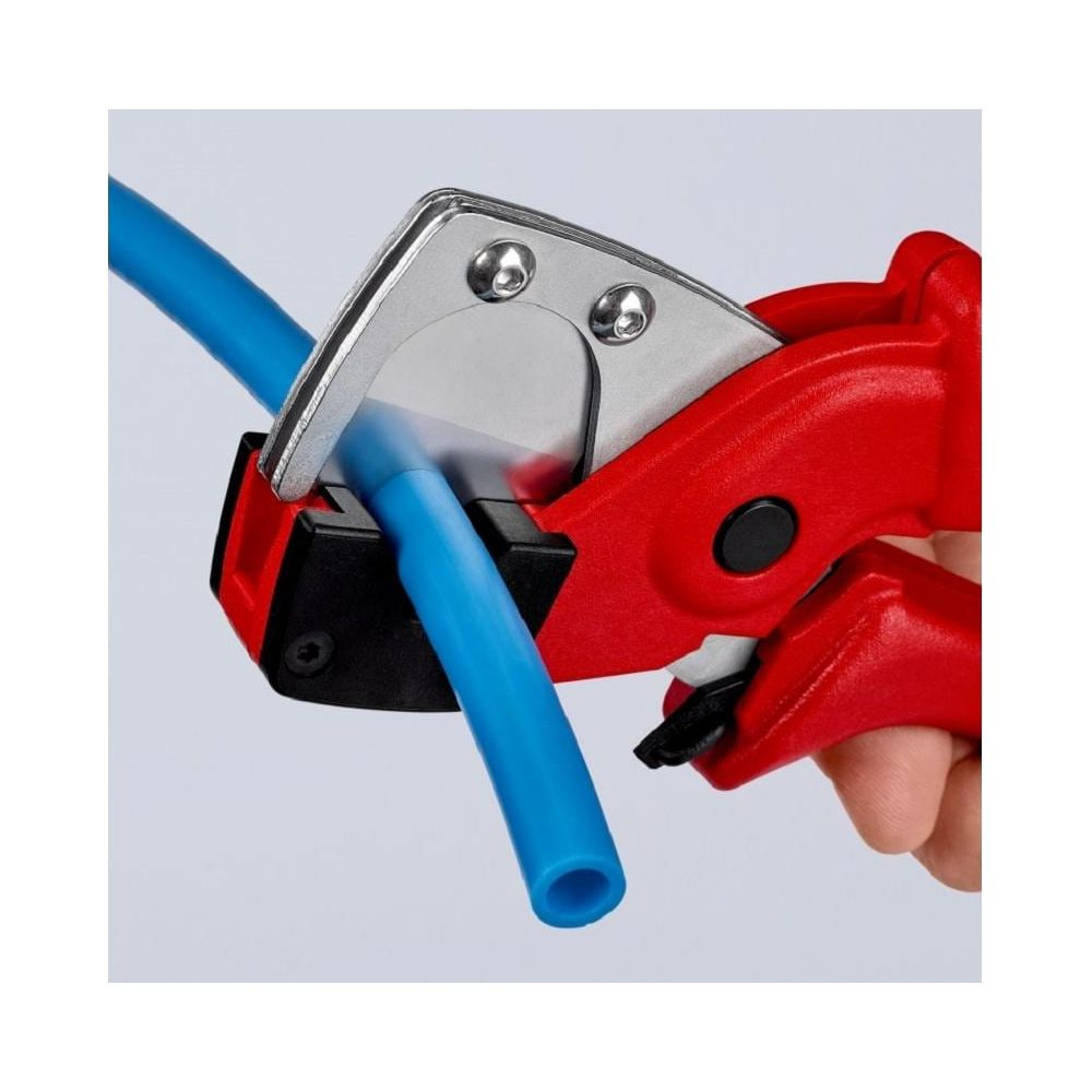 Tagliatubi rosso taglia un tubo di plastica blu. Utensile con lama metallica.