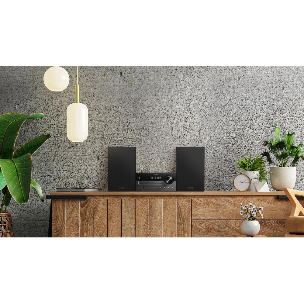Ein schwarzes Stereo-System steht auf einem Holzschrank neben Pflanzen und Lampen.