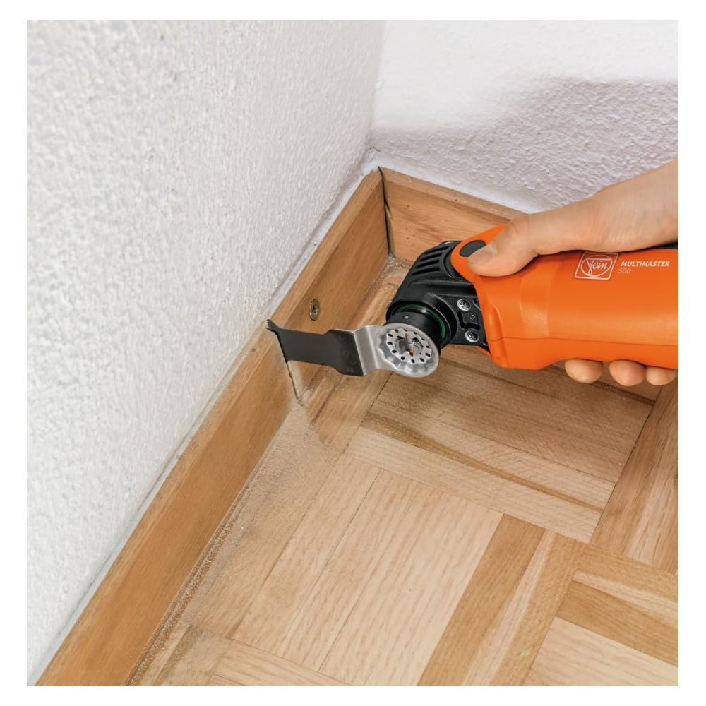 Pomarańczowe narzędzie wielofunkcyjne służy do cięcia drewnianej listwy przypodłogowej.