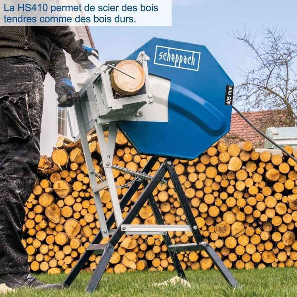Een man gebruikt een blauwe houtzaag met een stam, omringd door houtstapels.