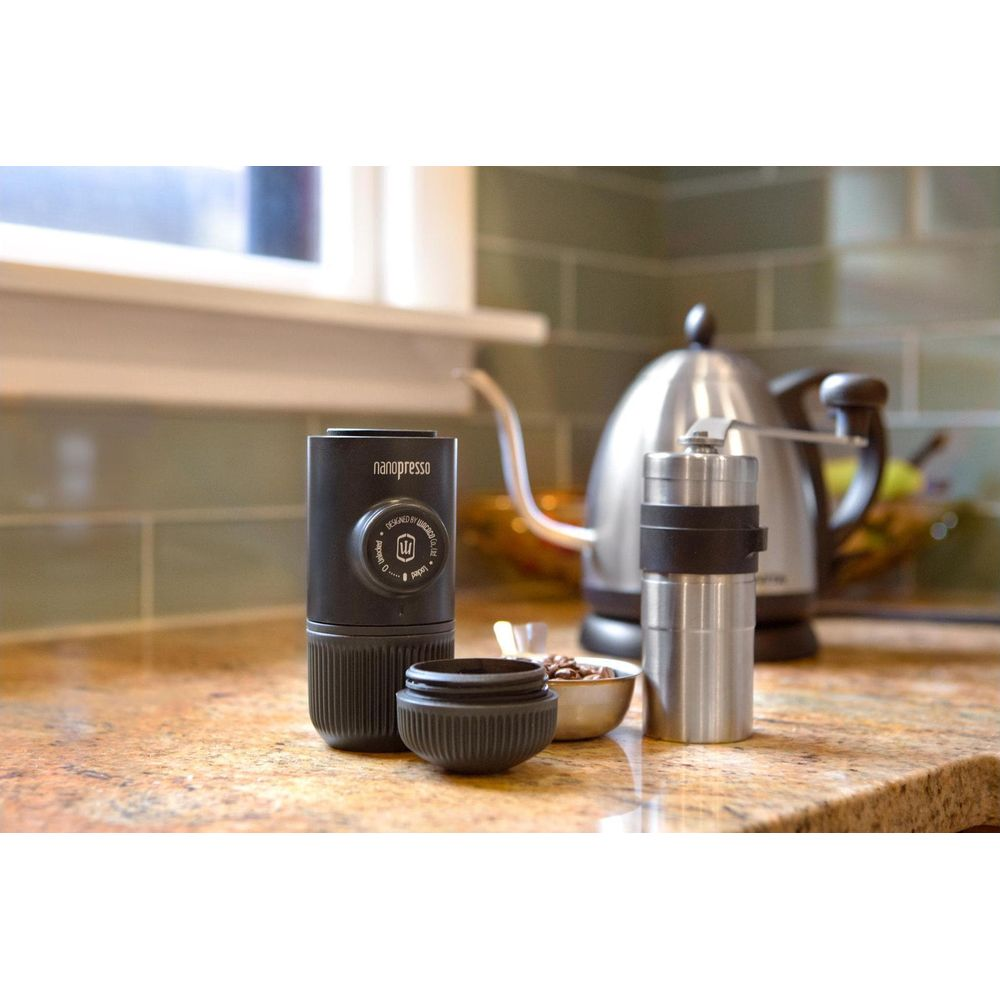 Czarny Nanopresso z młynkiem do kawy i czajnikiem na marmurowym blacie.