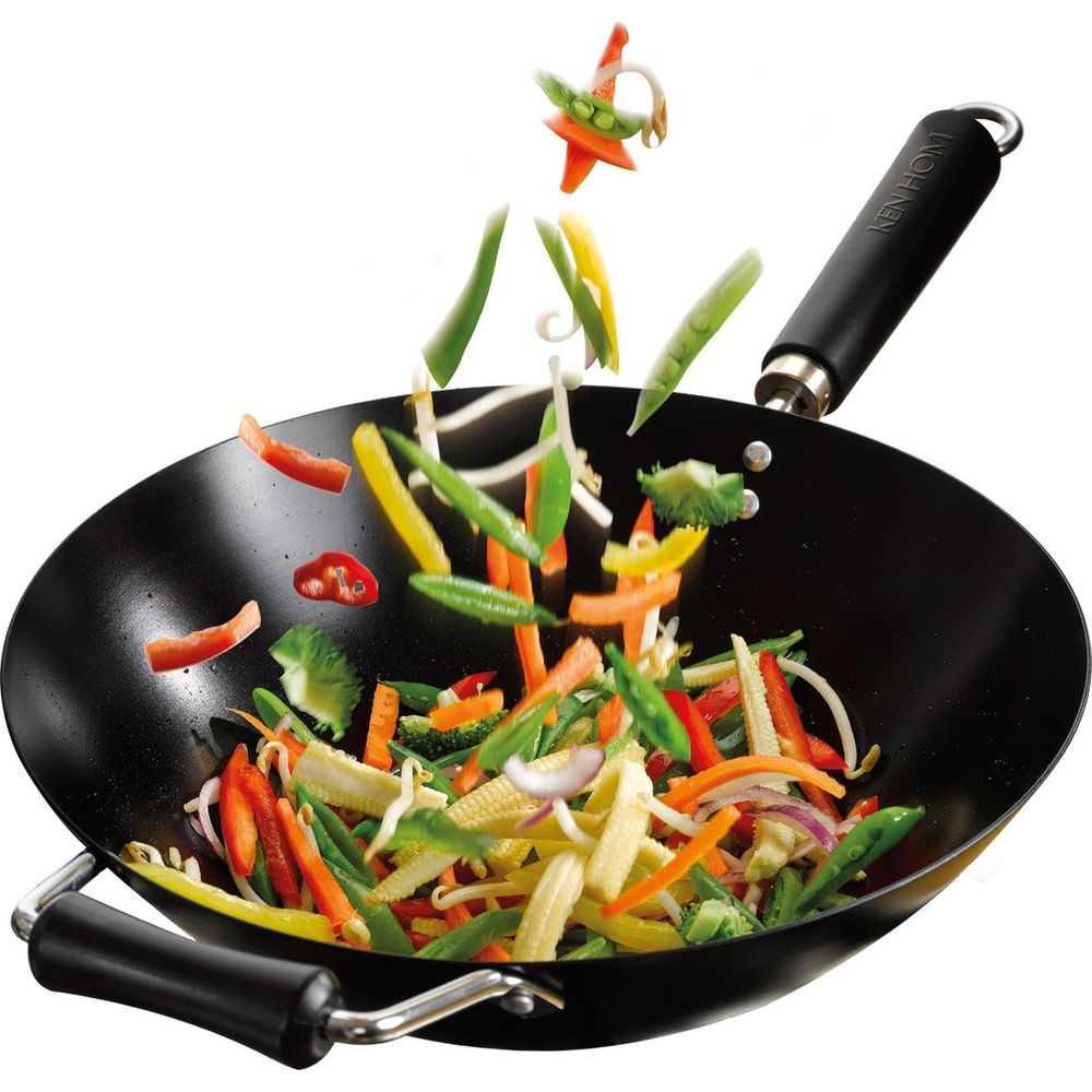 Légumes colorés volant dans un wok noir avec manche Ken Hom.