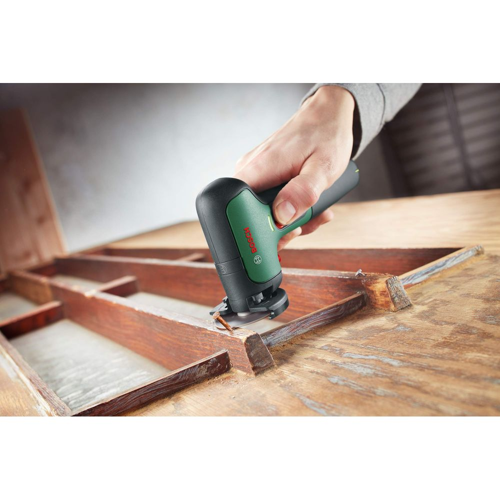 Hand hält Bosch Multifunktionswerkzeug an Holz.