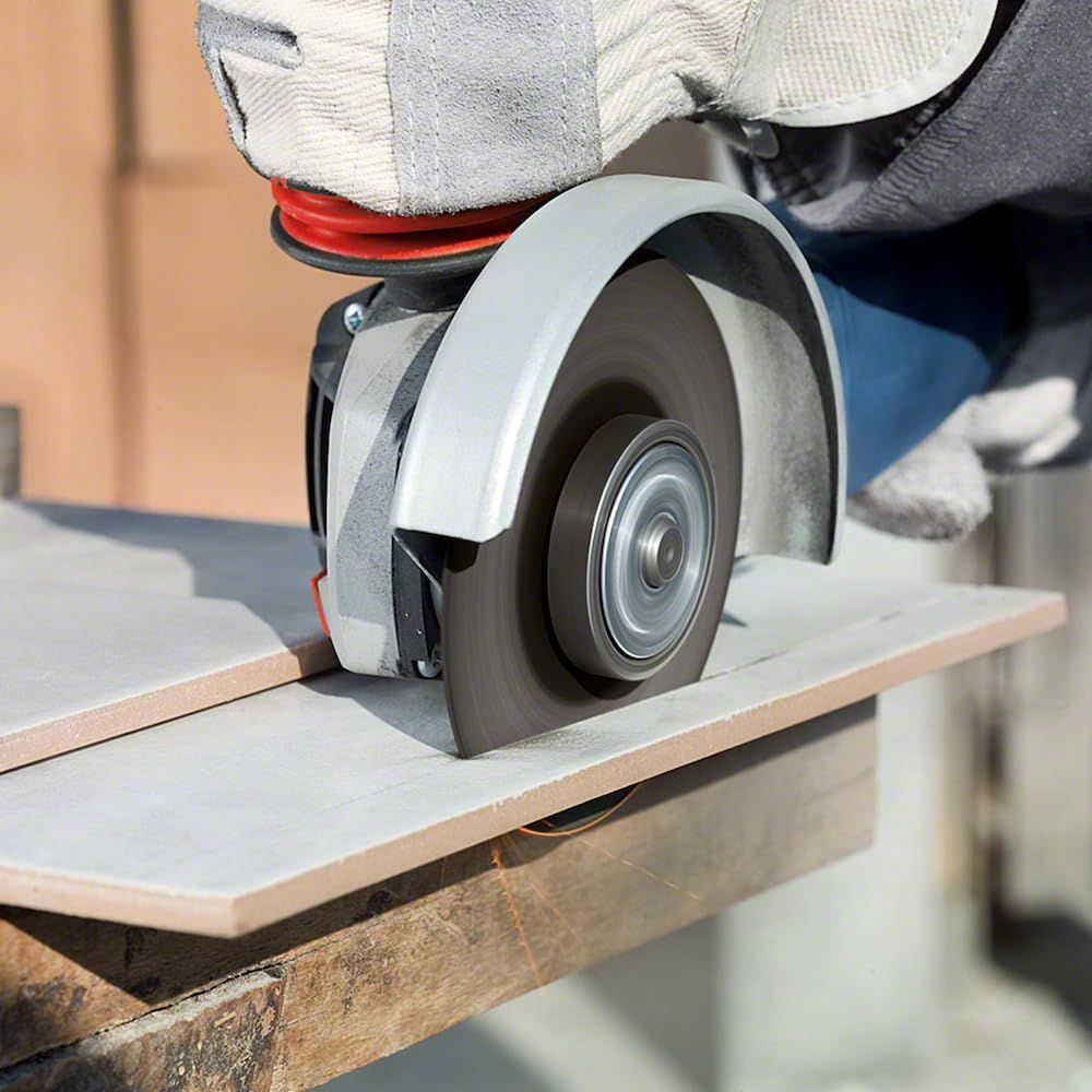 Pracownik tnie płytki szlifierką kątową. Iskry lecą.