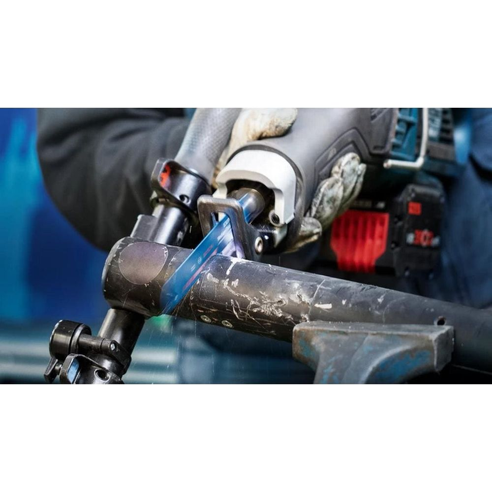 Osoba przecinająca metalową rurę brzeszczotem piły szablasty.