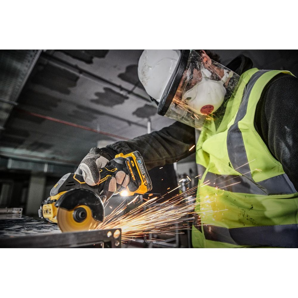 Trabajador con equipo de seguridad usa amoladora angular, creando chispas brillantes. Chispas vuelan del metal.