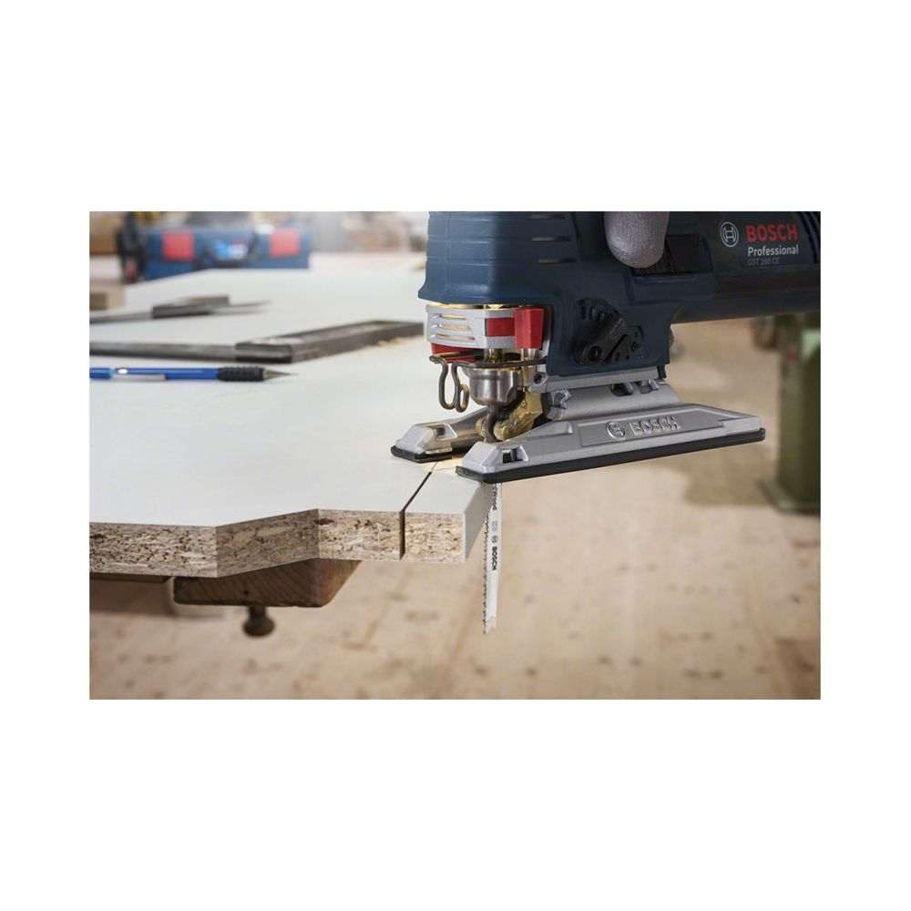 Bosch Stichsäge schneidet Holzplatte. Werkzeug in Nahaufnahme, Werkstatt im Hintergrund.