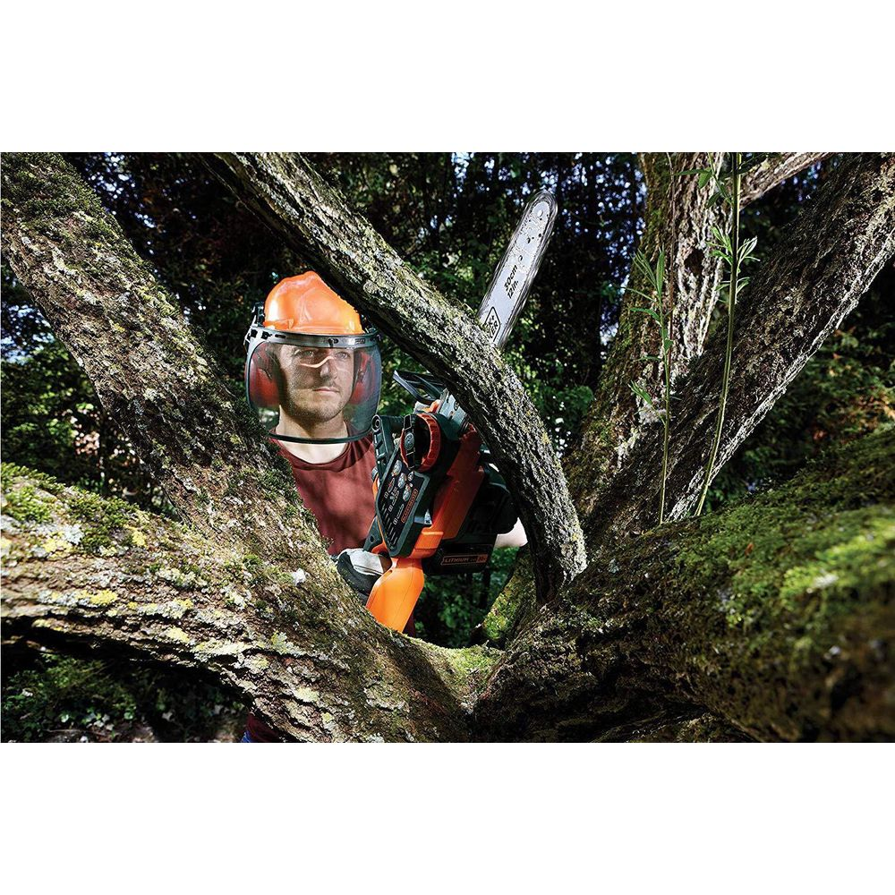 Mann mit orangefarbenem Helm und Gesichtsschutz hält Kettensäge in der Nähe von moosbewachsenen Ästen.