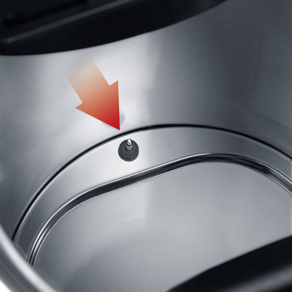 Une flèche rouge pointe vers une petite broche dans un conteneur en acier inoxydable.