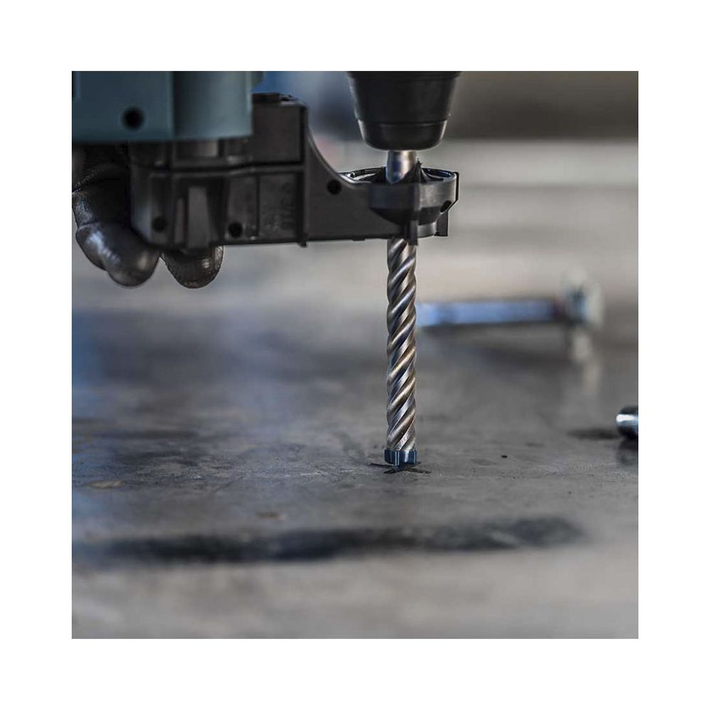 Une mèche de perceuse fore une surface en béton, tenue par une perceuse.